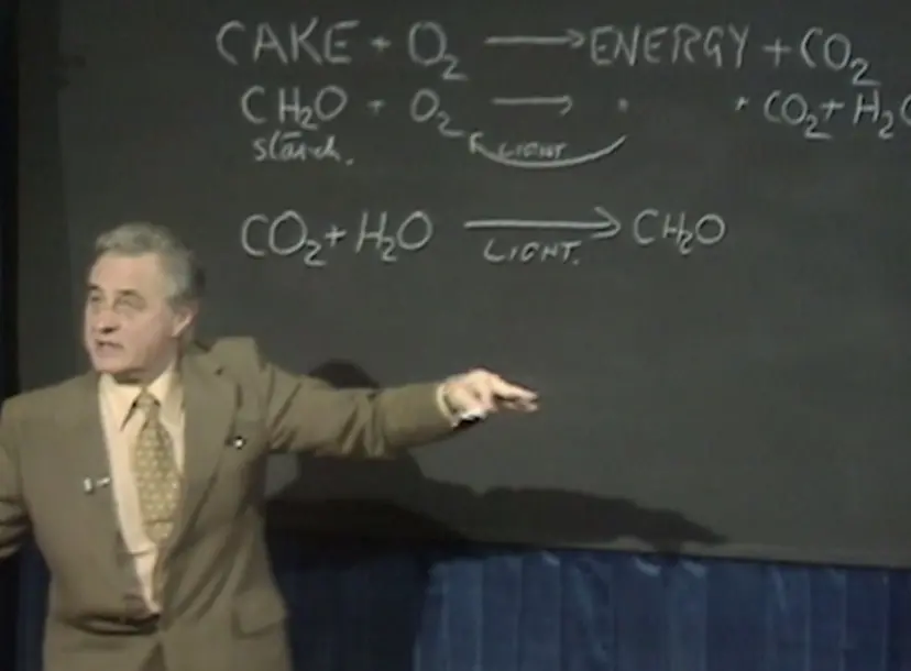 George Porter speaking, in from of a chalk board with equations he has written