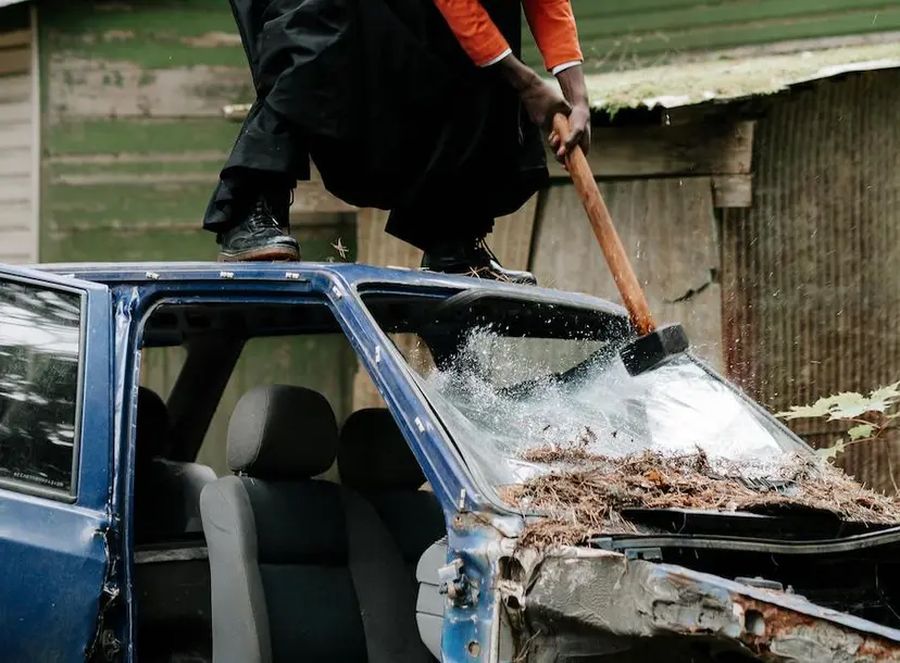 Person stood on a car smashing the windshield