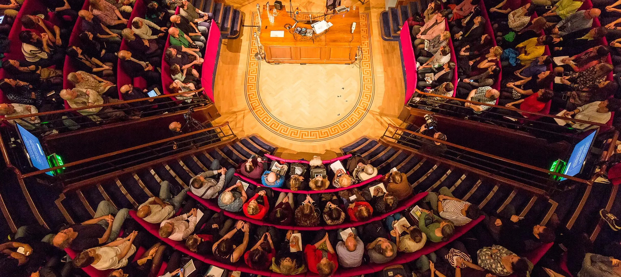a lecture theatre from above, the seats are curved around a central round stage like an old operating theatre