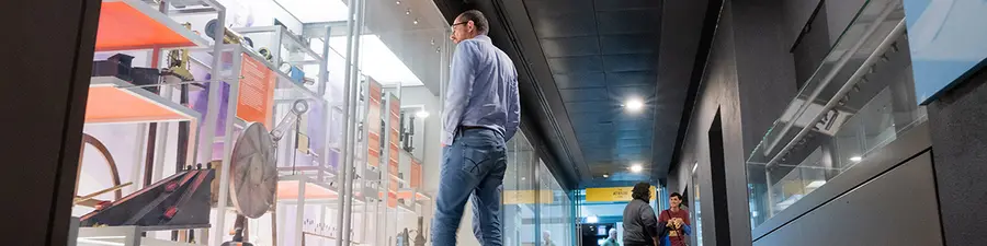 People looking at the displays behind glass walls in the Faraday museum