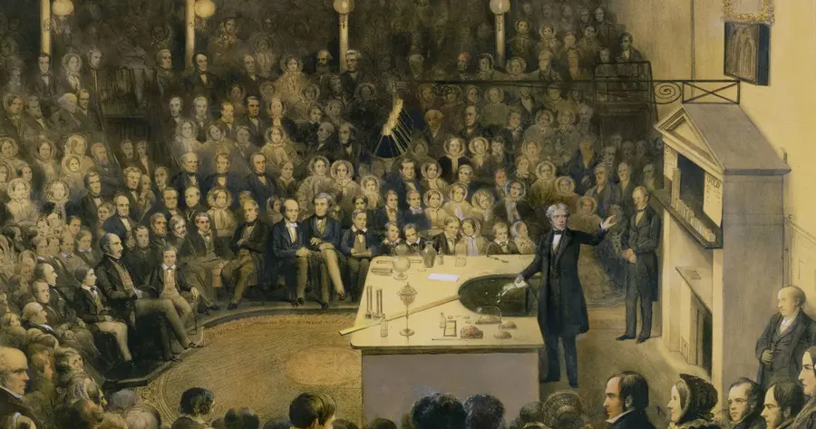 An engraving of Michael Faraday delivering a lecture to a packed audience in the Ri Theatre. We can see men, women and children attentively listening