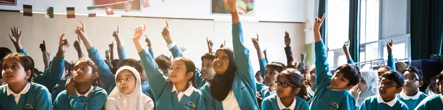 Children raising their hands to participate in a demo during a school visit