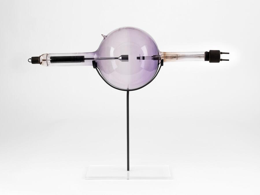 A glass sphere with glass tubes at either end and metal bars inside