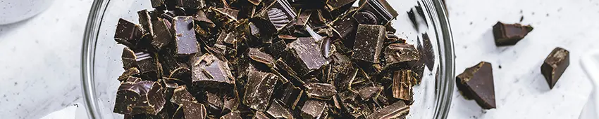 Chopped dark chocolate in a clear glass bowl