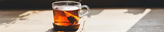 A bag of tea brewing in a clear cup