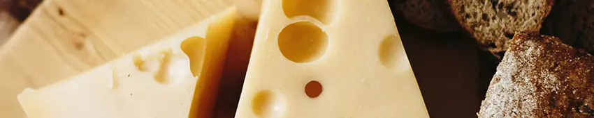 Some cheese with holes on a board with bread