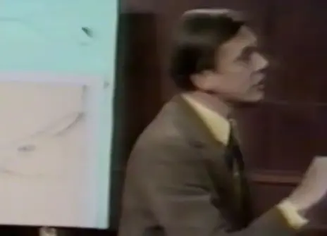 David Attenborough speaking in the Ri theatre, in front of a sketch of a rabbit head