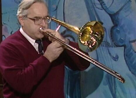 A man with glasses playing a trombone