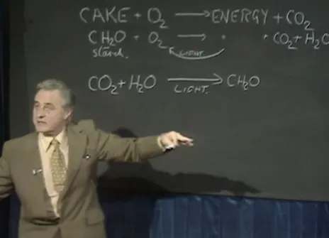 George Porter speaking, in from of a chalk board with equations he has written