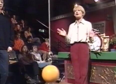 Nancy Rothwell stands between two hanging wires with coloured balls on the ends 
