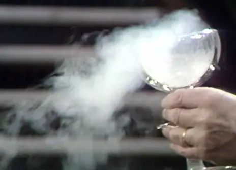 A glass goblet with smoke billowing out from it