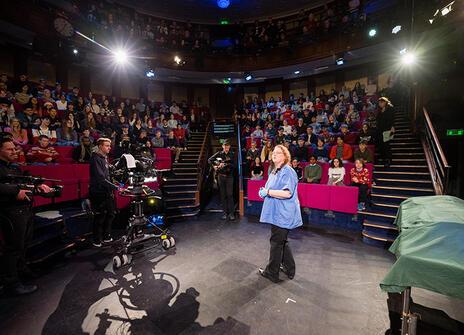 Sue Black standing in the middle of he Ri Theatre, in front of cameras and an audience