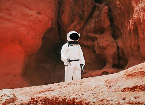 A person in a spacesuit among some red rocks