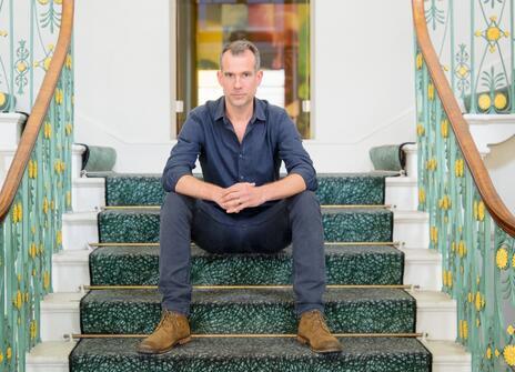 Chris Van Tulleken sitting on the grand staircase in the Royal Institution