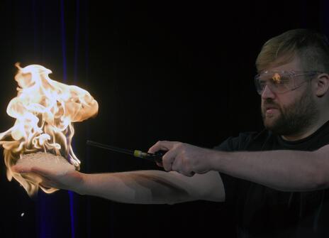 A science demonstrator at the Ri holding a flame