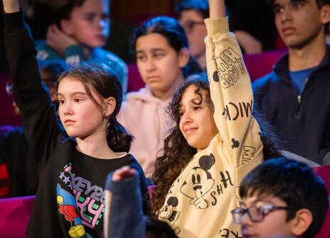 Young people with their hands up in the 2023 CHRISTMAS LECTURES audience