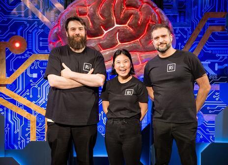 Three people in Ri t shirts stood in front of a large brain structure