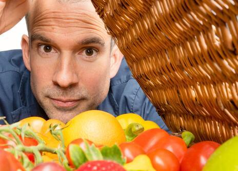 Chris peers into a basket containing fresh fruit and vegetables