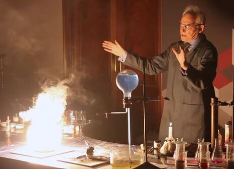 chemistry teacher Andrew Szydlo gesticulated towards a flaming experiment