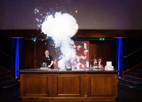 A person looks surprised as a eruption of sparks and smoke fills the air