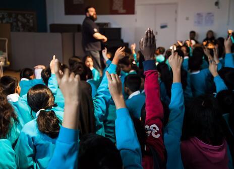 Children's hands go up in a science in schools presentation