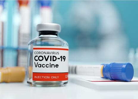 a covide 19 vaccine vial and syringe is shown