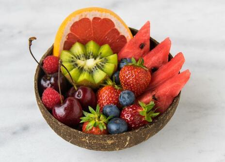 a bowl of fruit that includes kiwi, blood orange, strawberries and melon.