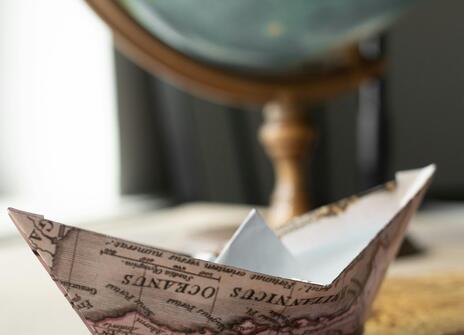 paper boat with globe in background