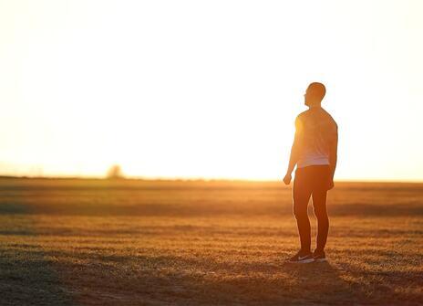 A man looks to the horizon on a meadow at golden hour